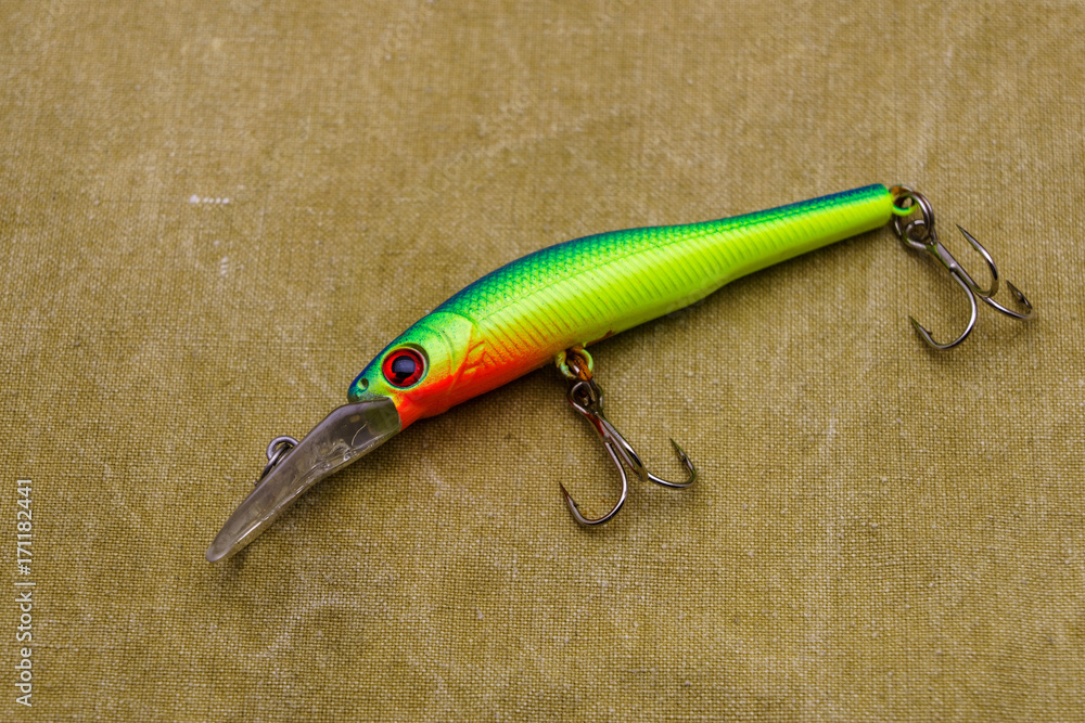 A bait for fishing on a tarpaulin background. Wobblers of different colors. A bait for fishing on a tarpaulin background. Wobblers of different colors.