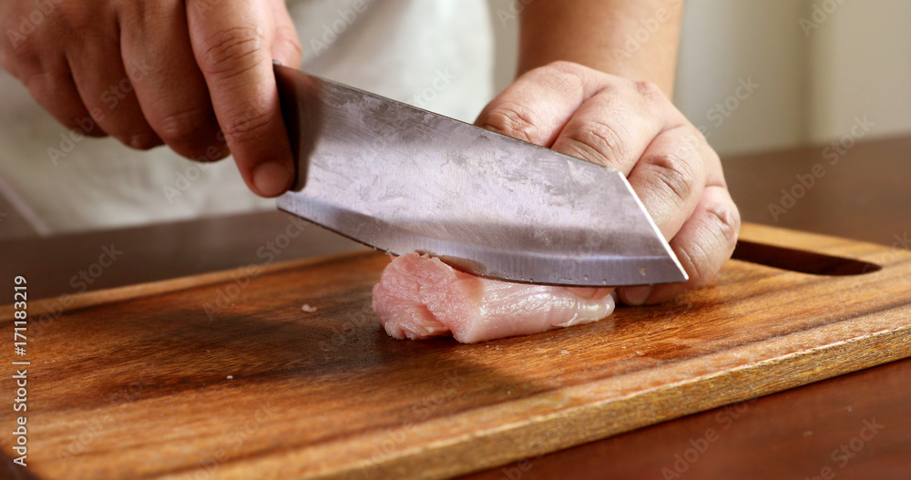 Close up the cutting raw chicken on wooden chop board