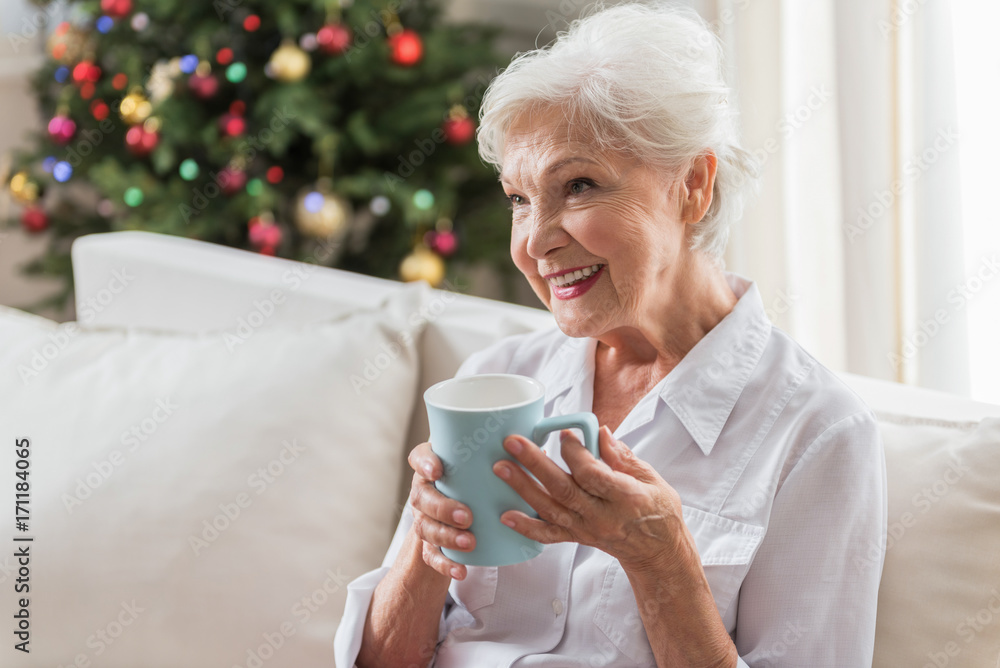 Positive elderly lady is relaxing on couch