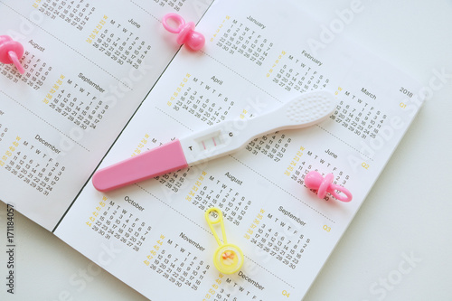 pregnant woman with pregnancy test watching calendar and calculating bith date