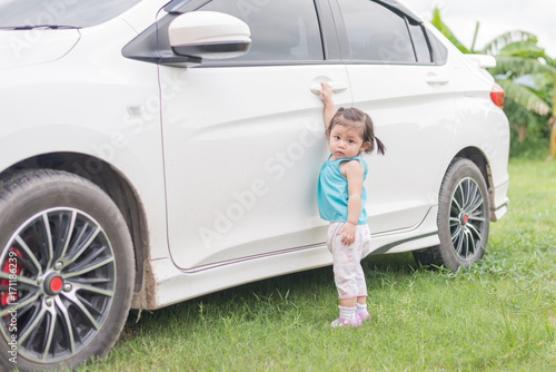 Asian cute baby girl try to open door car.