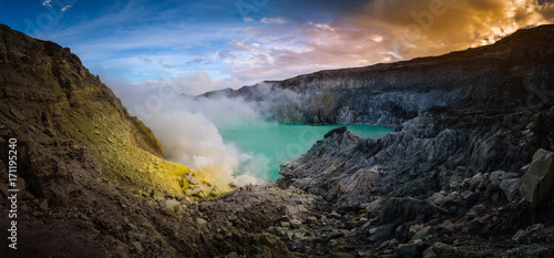 Kawah Ijen volcano with green lake on blue sky background at morning in East Java, Indonesia.