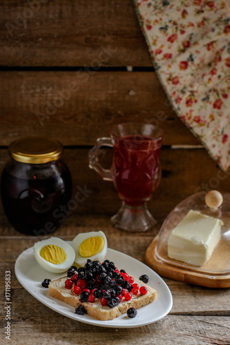 light breakfast (snack) a sandwich with blueberries and red currants, boiled eggs - in rustic style on a wooden surface 