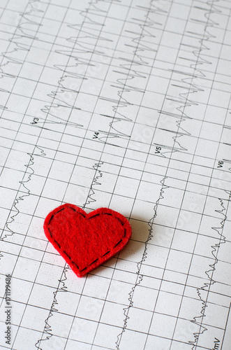 Electrocardiogram on paper.  Red heart made of fabric