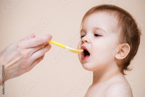 Mom feeds the baby with fruit puree