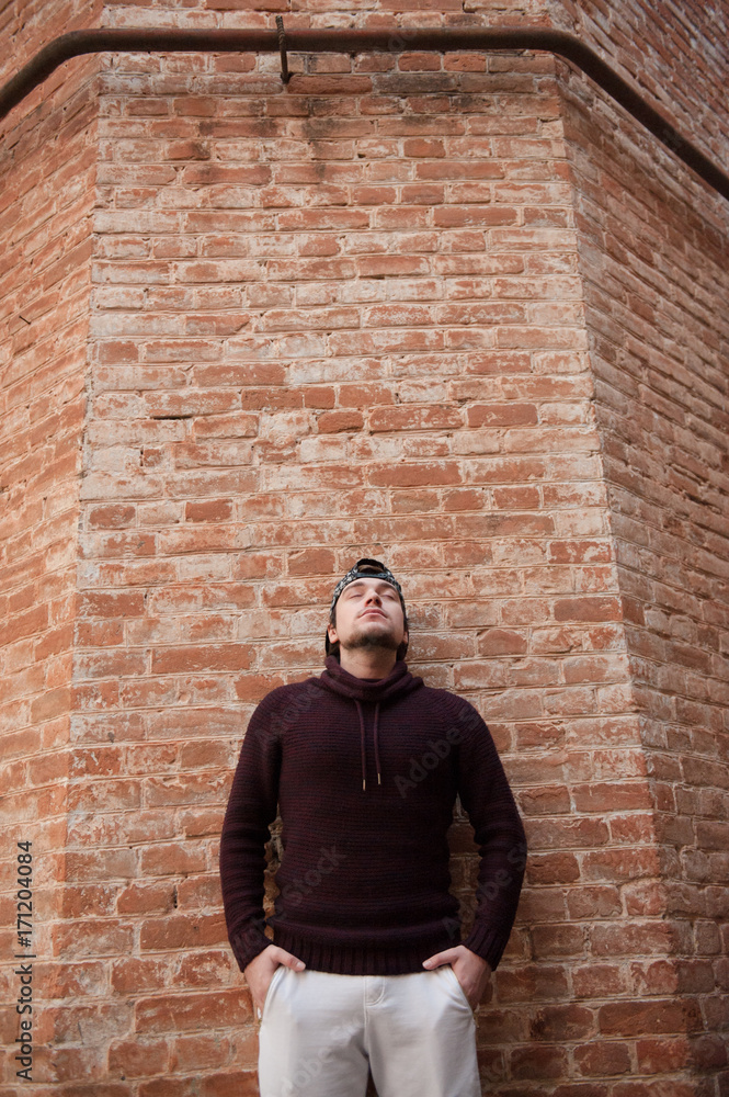 One young man stands on a brick wall background dreaming One young man stands on a brick wall background dreaming