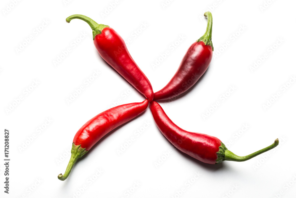 Four red chili peppers in the form of a cross on a white background. Four red chili peppers in the form of a cross on a white background.