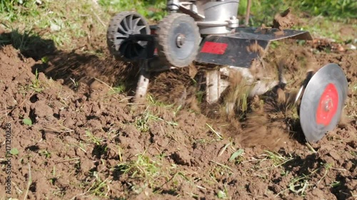 Wallpaper Mural A man is a farmer in a suburban area, a vegetable garden, plows the land with a cultivator, a manual motor plow, throwing clay and soil. Close-up of a cultivator of a tractor Torontodigital.ca