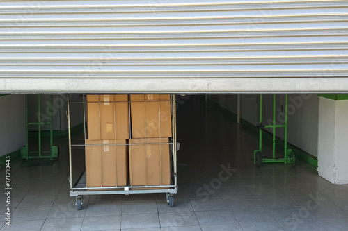 Entrance into self storage units, big cart with carton boxes in front, metal gate