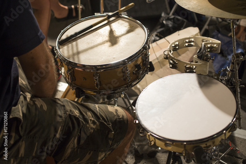 Dettaglio di un batterista mentre suona il suo strumento durante un concerto. In evidenza le bacchette e i tamburi centrali. photo
