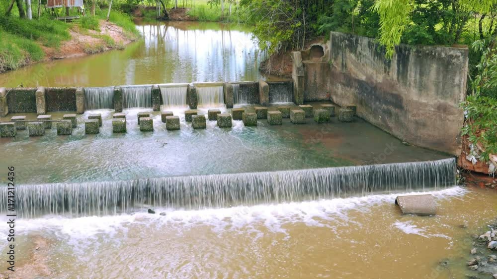 Continuous water movement scene of weir or dam to slow down the flow of water in the river. There are fresh green areas in Thailand. Continuous water movement scene of weir or dam to slow down the flow of water in the river. There are fresh green areas in Thailand.