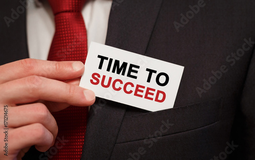 Businessman putting a card with text Time to succeed in the pocket