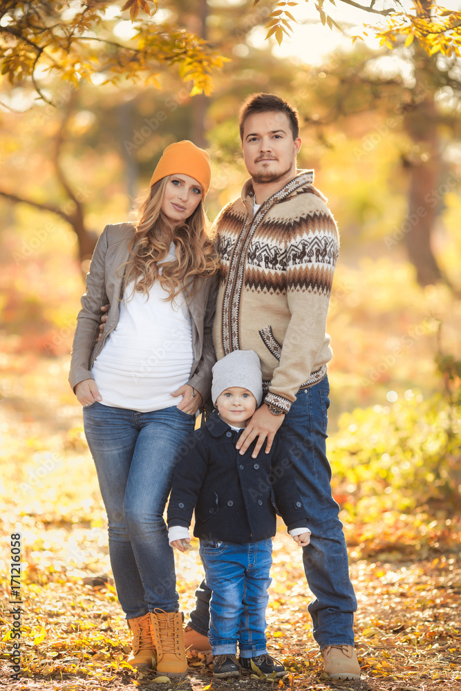 Young happy family have fun and walking in the autumn park. Pregnant woman with husband and little son Young happy family have fun and walking in the autumn park. Pregnant woman with husband and little son