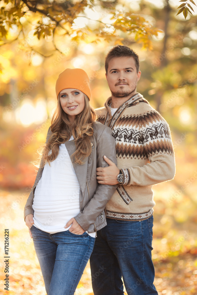 Fototapeta premium Young happy family have fun and walking in the autumn park. Pregnant woman with husband 