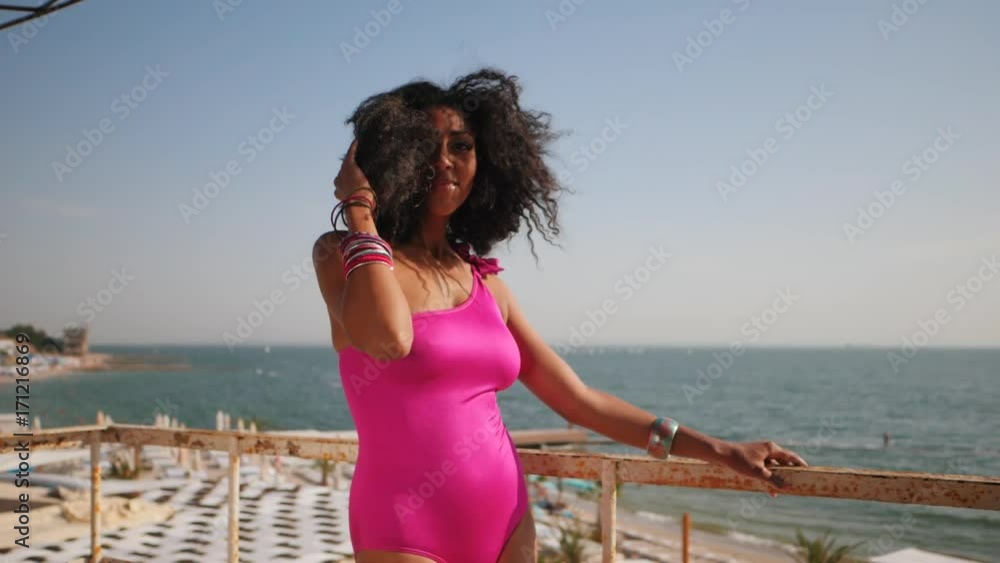 Beautiful mixed race mulatto woman in pink bikini posing on