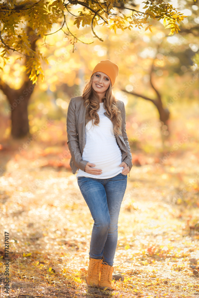 Young pregnant woman in casual clothes walking in autumn park Young pregnant woman in casual clothes walking in autumn park