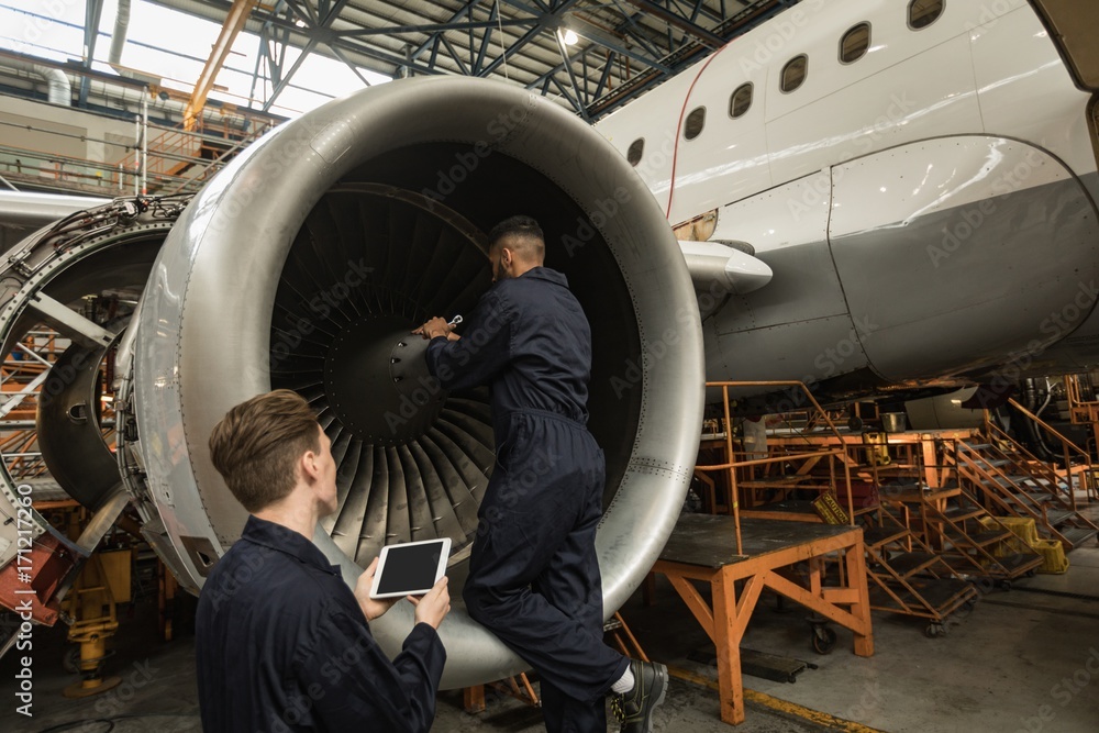 Aircraft maintenance engineers examining turbine engine of Aircraft maintenance engineers examining turbine engine of