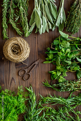 flat lay with fresh herbs and greenery for drying and making spices set on wooden kitchen background