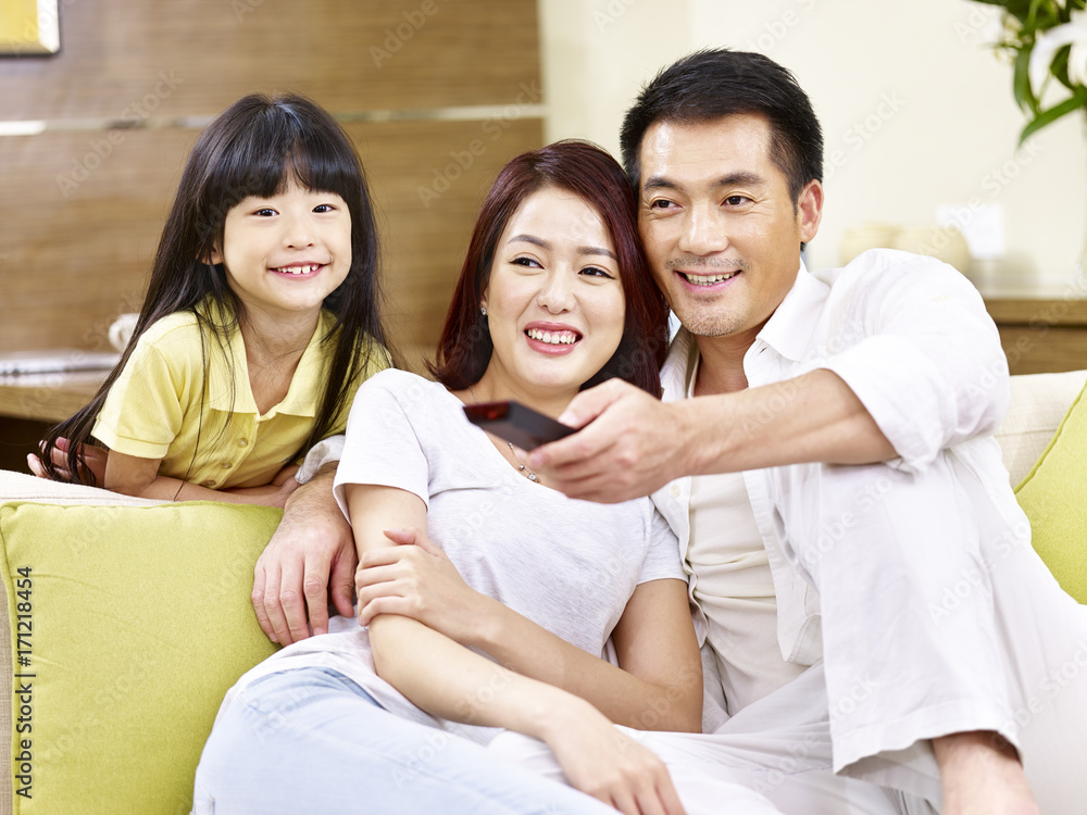 asian parents and daughter watching TV at home asian parents and daughter watching TV at home