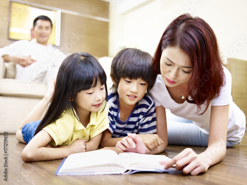 asian mother reading book with two children