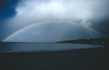 Rainbow in cloudy sky across coastline