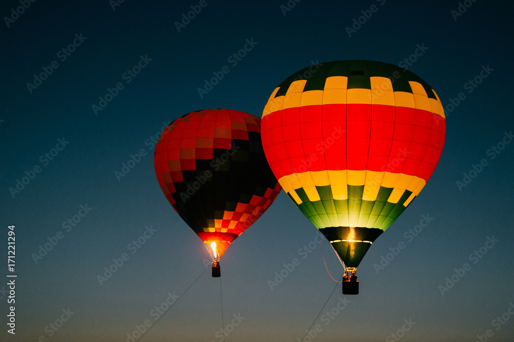 Naklejka premium Glowing and blinking balloons flight with people high in sky in night. Freedom concept. Romantic recreation. Hot air balls competition. Autumn ballooning festival. Travel and tourism. Airship journey.