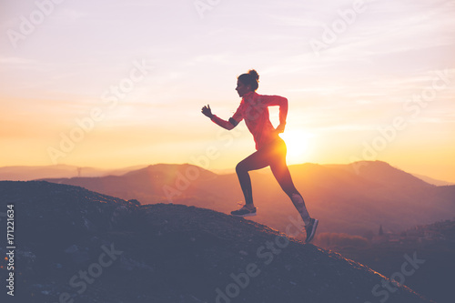 Athletic girl finishes a run in the mountains at sunset. Sport tight clothes. Intentional motion blur. © Alex from the Rock