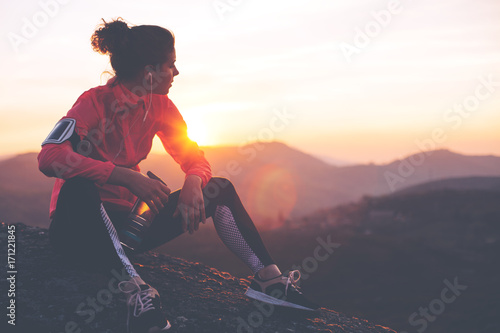 Wysportowana kobieta odpoczywa po ciężkim treningu w górach o zachodzie słońca Obcisłe ubrania sportowe