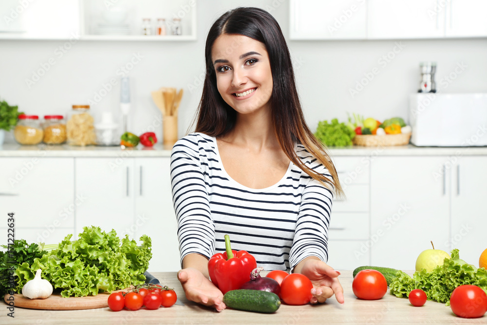 Beautiful young woman with vegetables in the kitchen