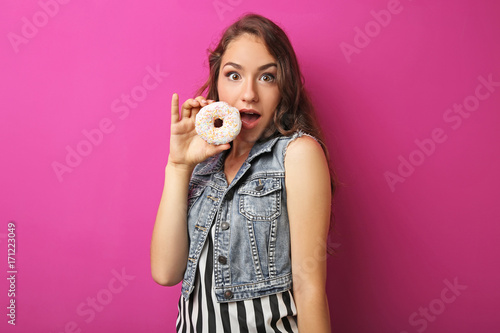 Portrait of young woman with sweet donut on pink background