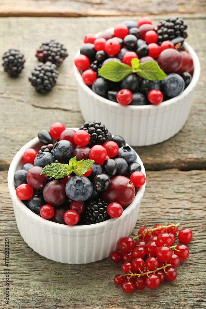 Ripe and sweet berries in bowls on wooden table Ripe and sweet berries in bowls on wooden table