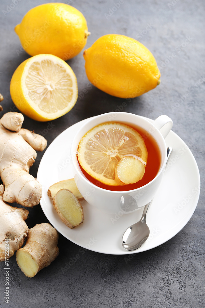 Cup of tea with ginger root and lemon on grey wooden table Cup of tea with ginger root and lemon on grey wooden table