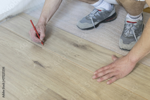  Carpenter worker installing laminate flooring in the room