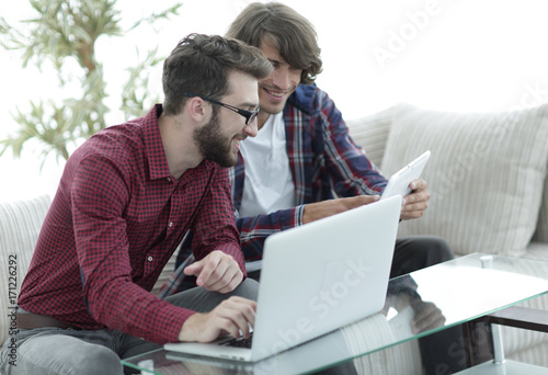 Portrait of two web designers discussing a project in front of a laptop