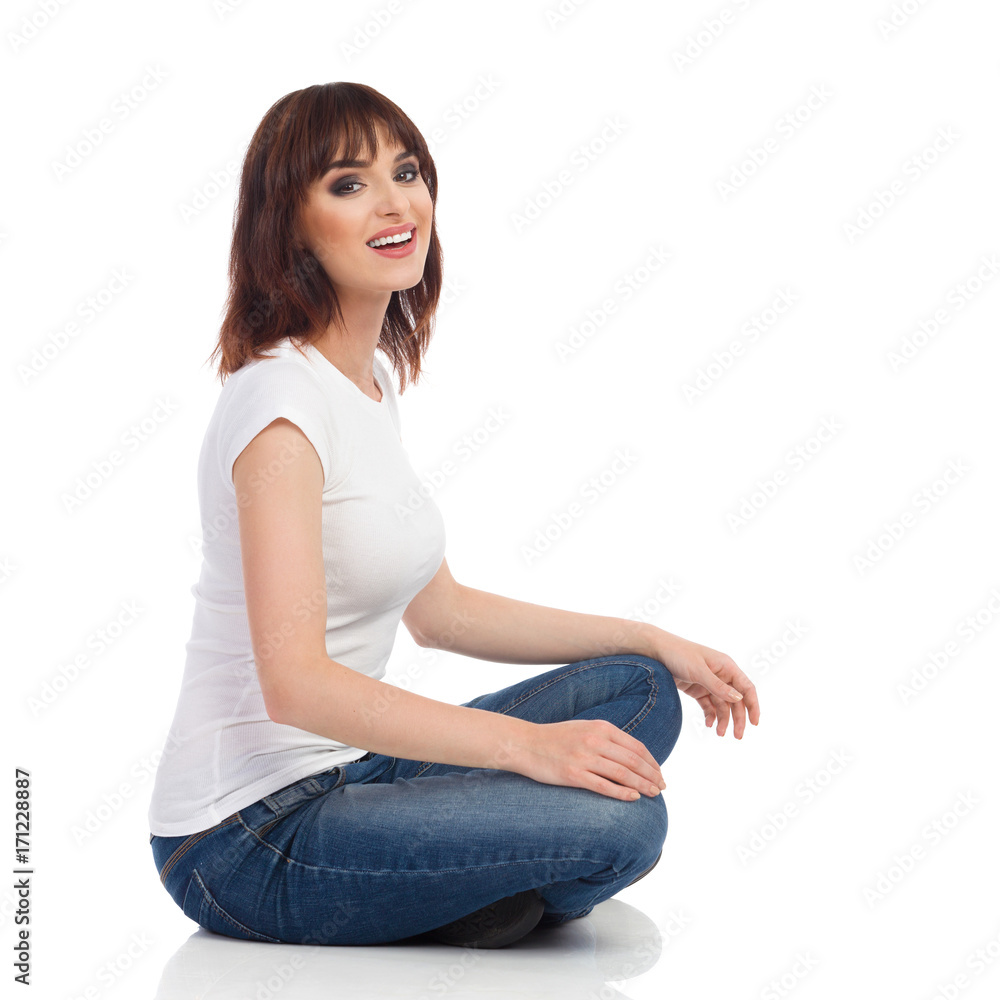 Smiling Young Woman Is Sitting On A Floor With Crossed Legs And Looking At Camera Smiling Young Woman Is Sitting On A Floor With Crossed Legs And Looking At Camera