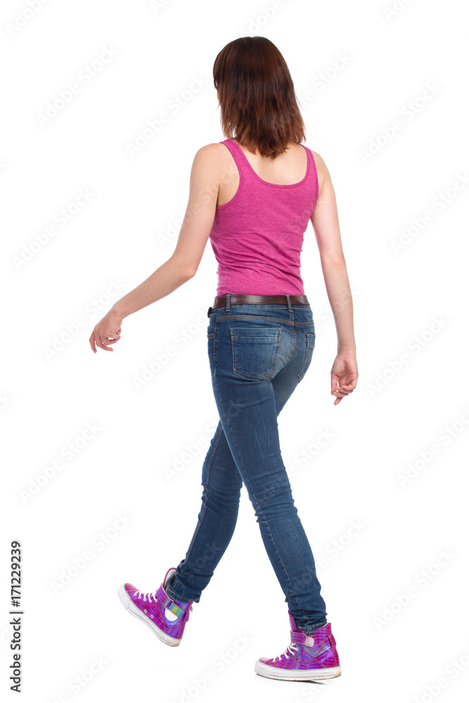 Walking Woman In Pink Tank Top. Jeans And Sneakers. Rear Side View. Walking Woman In Pink Tank Top. Jeans And Sneakers. Rear Side View.