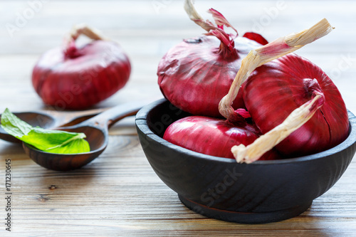 Sweet red onions in a black wooden bowl.