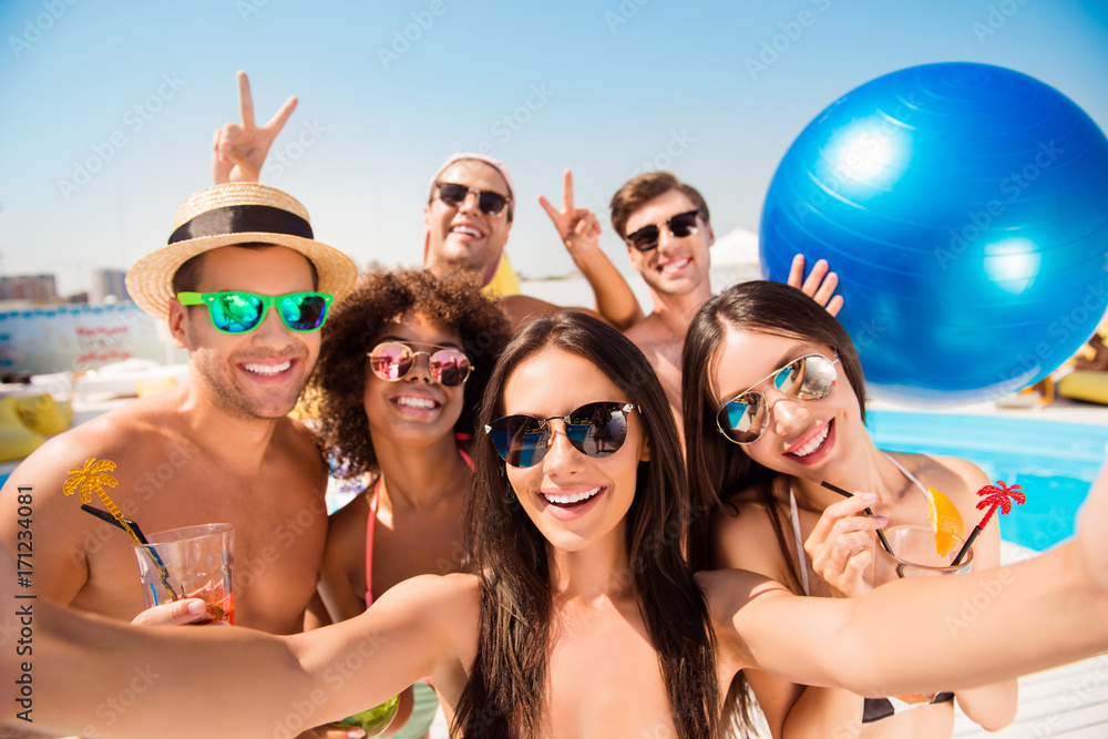 Selfie time! Six cheerful friends in fashionable different swim wear and sun protecting eyewear, caps, with drinks are posing for a selfie photo, that brunette lady is taking, beaming smiles, sunshine Selfie time! Six cheerful friends in fashionable different swim wear and sun protecting eyewear, caps, with drinks are posing for a selfie photo, that brunette lady is taking, beaming smiles, sunshine