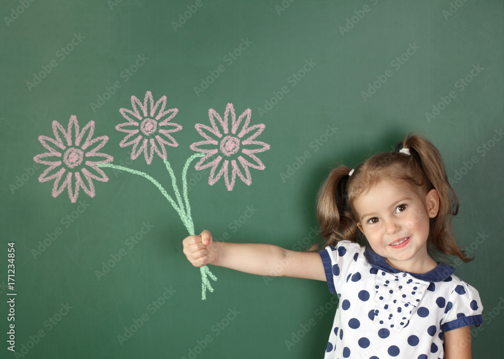 Smiling child girl hold drawn flowers near school blackboard