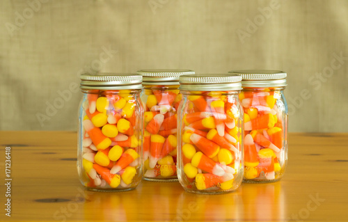  4 mason jars filled with candy corn on a wooden table