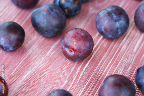 Ripe plums on a pink wooden background