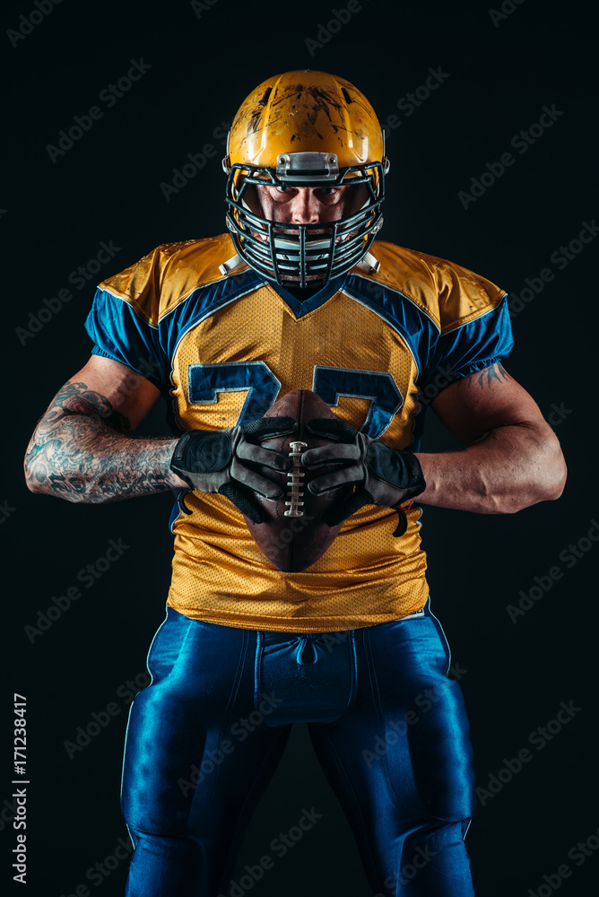 Fototapeta American football player holds ball in hands