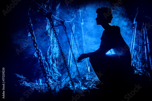 Obraz na płótnie Silhouette of a mysterious witch on the suspension bridge with clouds of smoke around her