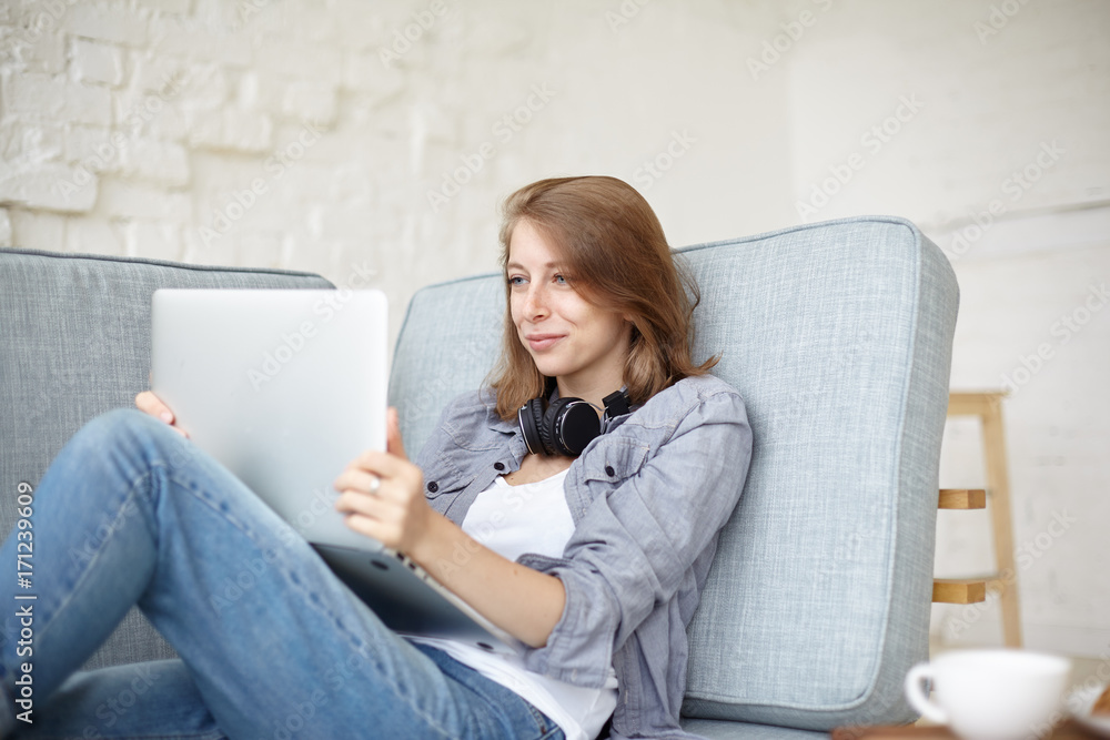 Attractive young female with fair hair resting with generic laptop pc, making video conference call or watching something funny on internet. People, technology, online communication and entertainment Attractive young female with fair hair resting with generic laptop pc, making video conference call or watching something funny on internet. People, technology, online communication and entertainment