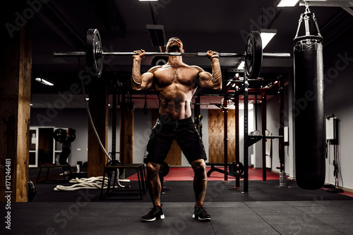 Muscular fitness man doing deadlift a barbell over his head in modern fitness center. Functional training. Snatch exercise photo