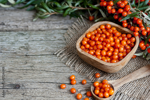 Sea buckthorn oil bottle with a small bowl of sea-buckthorn berries