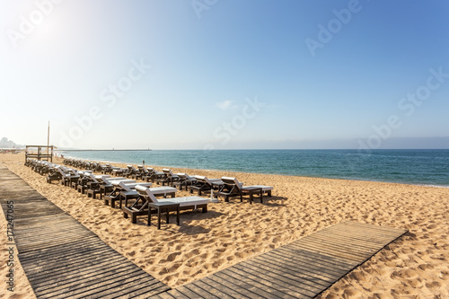 Rows of sunbeds for sunbathing on the beach in the Algarve. © sergojpg