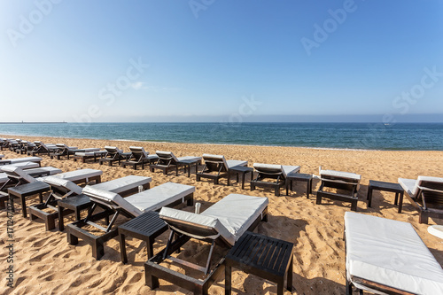 Row of sun beds for sunbathing close-up on beach in the Algarve. © sergojpg