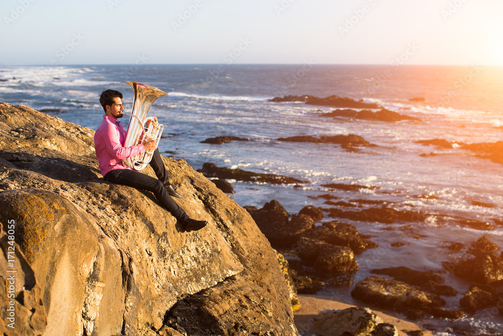 Musician playing the Tuba on the sea shore.