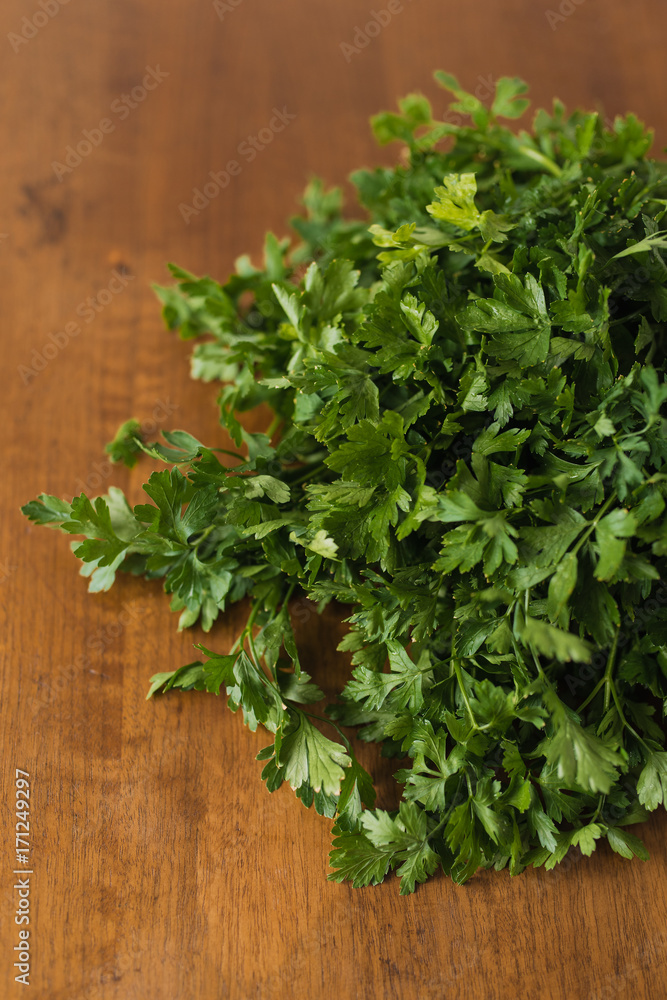 Bunch of fresh garden parsley stems with little imperfections on wooden background Bunch of fresh garden parsley stems with little imperfections on wooden background
